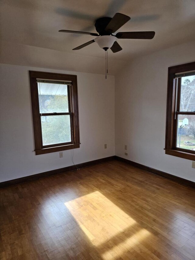 spare room featuring ceiling fan, dark hardwood / wood-style flooring, and plenty of natural light