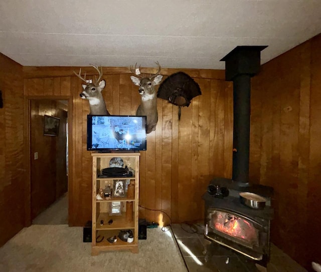 interior space with carpet flooring, a wood stove, and wood walls