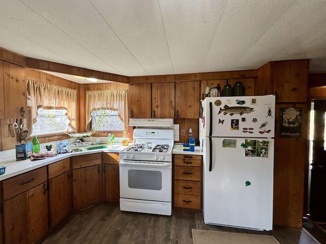 kitchen with white appliances, sink, wooden walls, dark hardwood / wood-style floors, and a textured ceiling