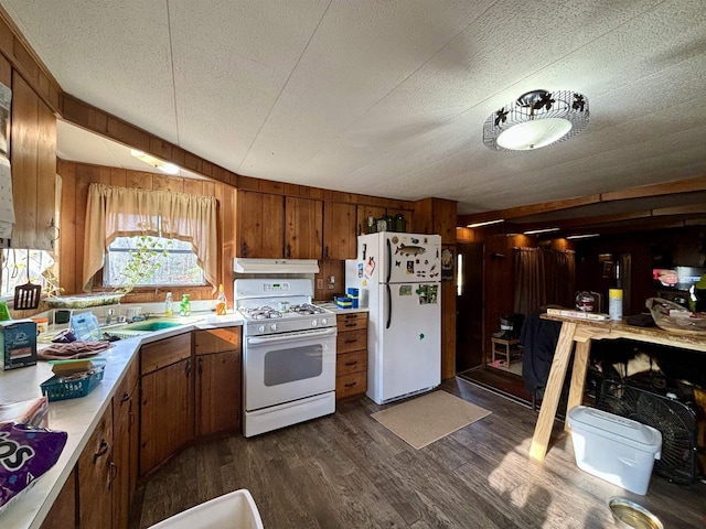 kitchen with a textured ceiling, wooden walls, dark hardwood / wood-style flooring, and white appliances