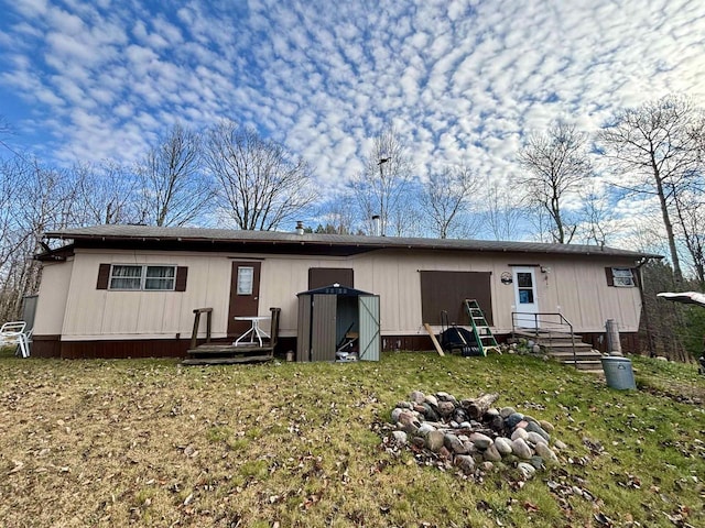 rear view of property with a yard and a fire pit