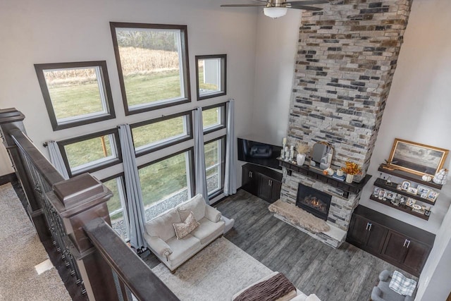 living room featuring a towering ceiling, a fireplace, plenty of natural light, and ceiling fan