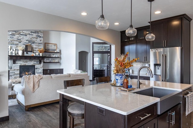 kitchen with a stone fireplace, decorative light fixtures, dark hardwood / wood-style flooring, sink, and high quality fridge