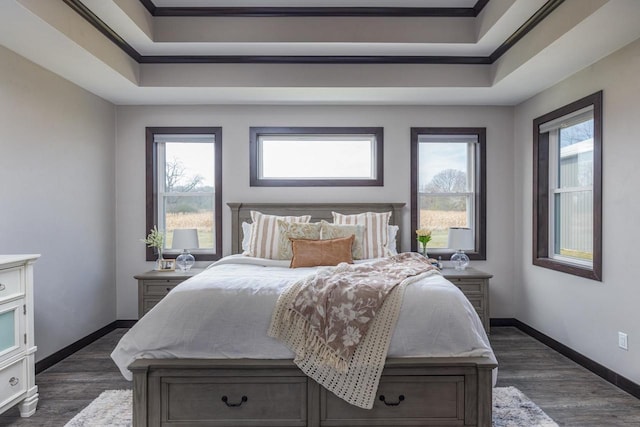 bedroom featuring crown molding, dark hardwood / wood-style flooring, and a tray ceiling