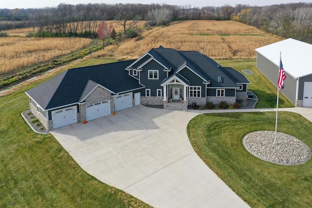 view of front of home with a garage, a rural view, and a front lawn