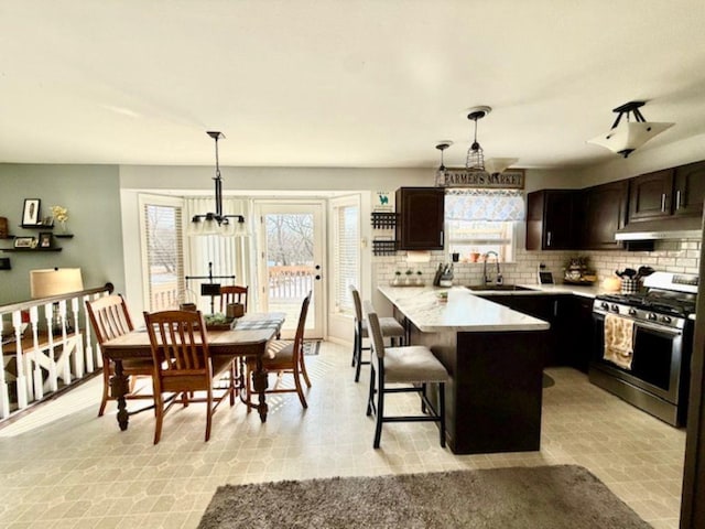 N4266 Cherokee Ct, Markesan, WI 53946 - kitchen featuring stainless steel gas range, light countertops, a peninsula, under cabinet range hood, and backsplash