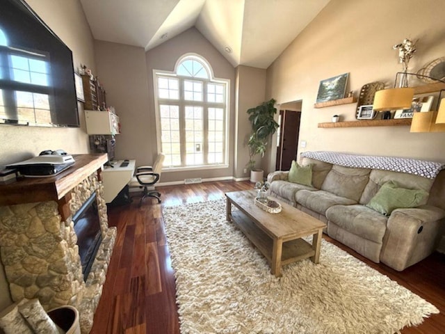 N4266 Cherokee Ct, Markesan, WI 53946 - living area with dark wood finished floors, vaulted ceiling, a stone fireplace, and baseboards