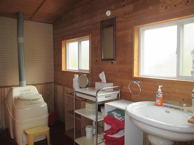 bathroom with wood ceiling, wooden walls, and sink