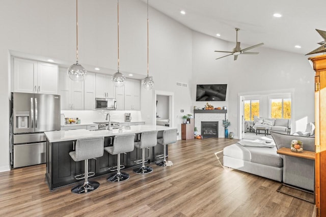 kitchen with white cabinets, stainless steel appliances, high vaulted ceiling, and pendant lighting