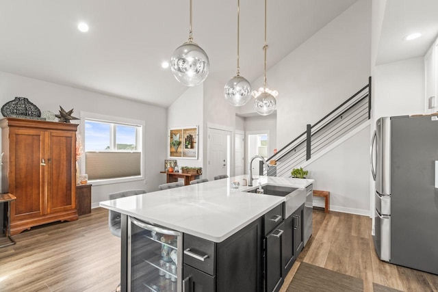 kitchen featuring stainless steel fridge, a kitchen island with sink, light wood-type flooring, and beverage cooler