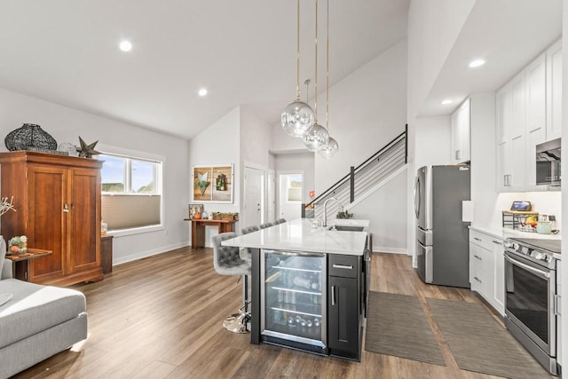 kitchen with stainless steel appliances, pendant lighting, beverage cooler, white cabinetry, and dark hardwood / wood-style flooring