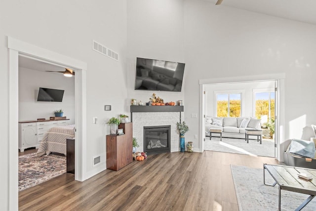 living room featuring ceiling fan, high vaulted ceiling, and wood-type flooring