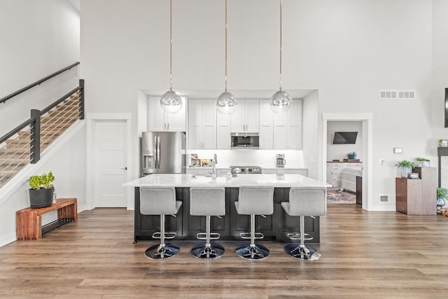 kitchen featuring appliances with stainless steel finishes, light hardwood / wood-style flooring, white cabinetry, and pendant lighting