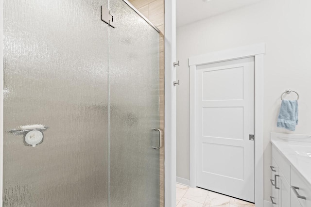 bathroom featuring a shower with door and vanity