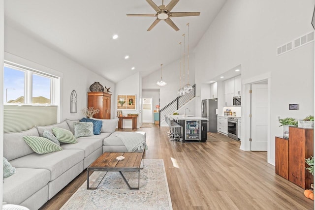 living room with sink, high vaulted ceiling, light hardwood / wood-style floors, and ceiling fan