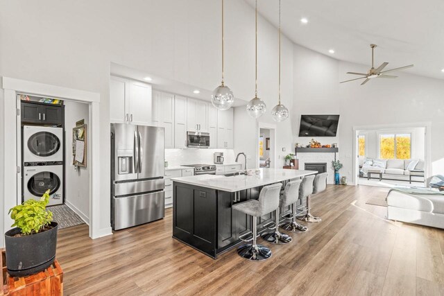 6556 Vista Vly Unit 2, Windsor, WI 53598 - kitchen with appliances with stainless steel finishes, stacked washer and clothes dryer, open floor plan, high vaulted ceiling, and white cabinets