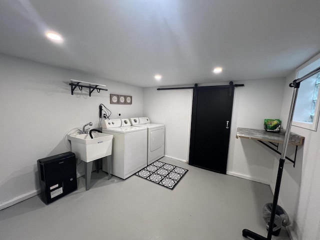 laundry area with washing machine and dryer, a barn door, and sink