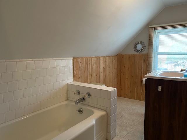 bathroom featuring vaulted ceiling, tile patterned flooring, a bath, and vanity