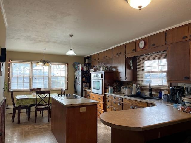 kitchen with decorative light fixtures, a notable chandelier, oven, a kitchen island, and sink