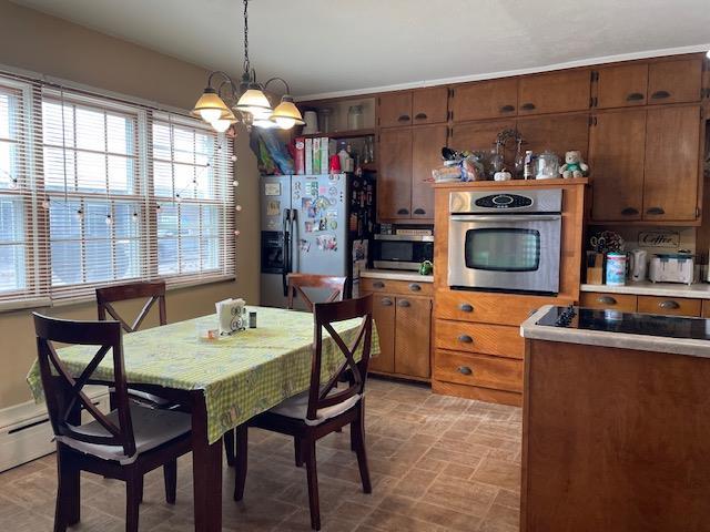 dining area with a wealth of natural light, a baseboard heating unit, and a chandelier