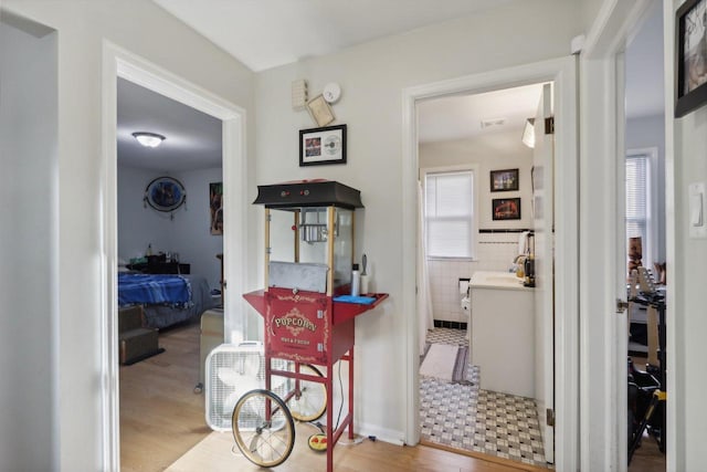 corridor with tile walls and light hardwood / wood-style floors