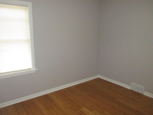 empty room with hardwood / wood-style flooring and a healthy amount of sunlight