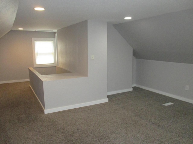 additional living space featuring vaulted ceiling and dark carpet