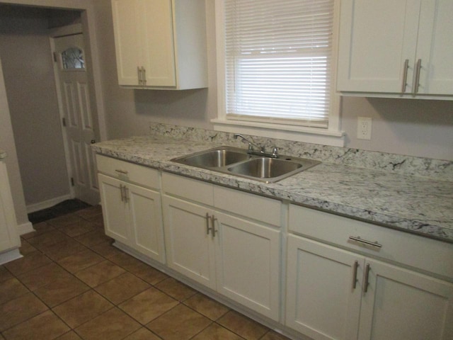 kitchen with light stone countertops, tile patterned floors, sink, and white cabinetry