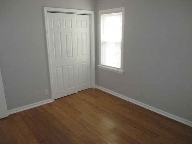 unfurnished bedroom featuring a closet and dark hardwood / wood-style flooring