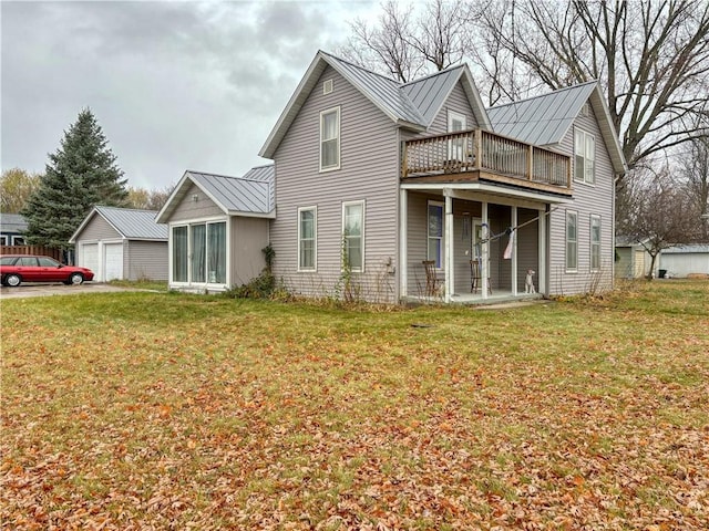 rear view of property featuring an outdoor structure, a sunroom, and a yard