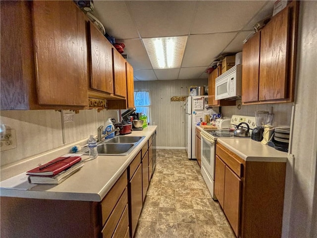 kitchen with white appliances, sink, and a drop ceiling