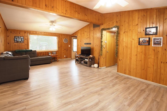 living room featuring ceiling fan, wooden walls, and light wood-type flooring