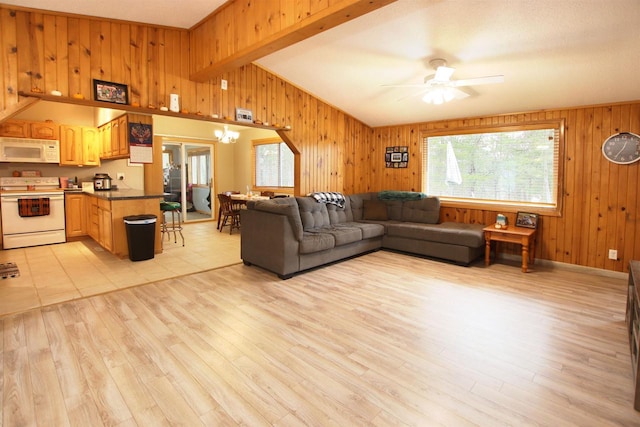 living room with ceiling fan with notable chandelier, wooden walls, light hardwood / wood-style flooring, and lofted ceiling with beams