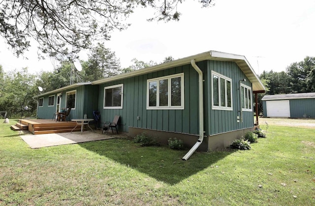 back of house featuring an outbuilding, a lawn, and a wooden deck