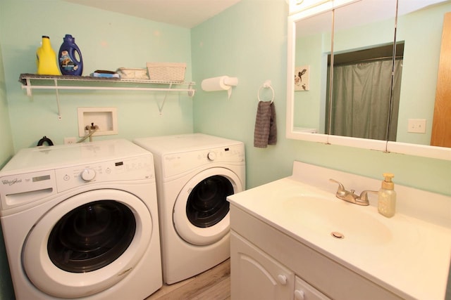 laundry room with washer and dryer, sink, and light hardwood / wood-style flooring