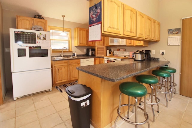 kitchen with white appliances, a kitchen bar, hanging light fixtures, sink, and kitchen peninsula