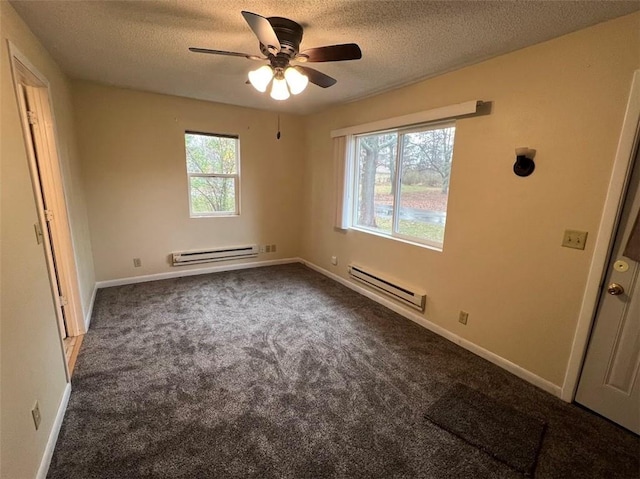 carpeted empty room with a baseboard radiator, plenty of natural light, and a textured ceiling