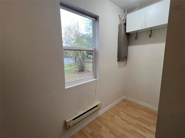 laundry room with a wealth of natural light, a baseboard radiator, and light wood-type flooring