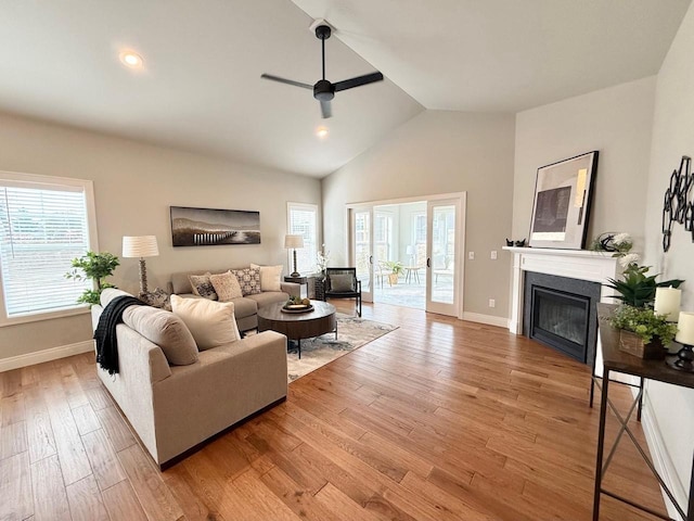 living room with ceiling fan, light wood-type flooring, and high vaulted ceiling