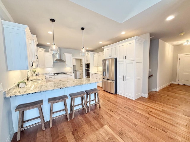 kitchen with white cabinetry, stainless steel appliances, hanging light fixtures, and light hardwood / wood-style flooring