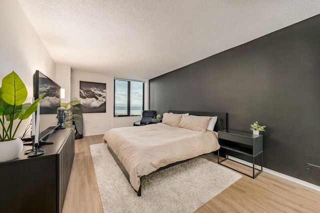 bedroom with a textured ceiling and light hardwood / wood-style floors