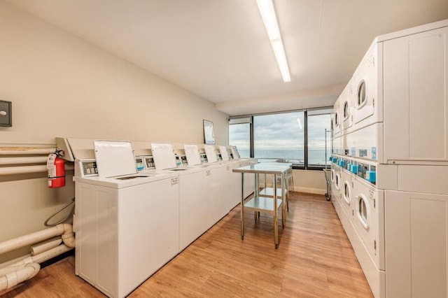 washroom with stacked washing maching and dryer, washing machine and dryer, and light hardwood / wood-style floors