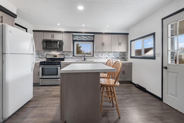 kitchen with gray cabinets, a kitchen island, stainless steel range with gas cooktop, and white fridge