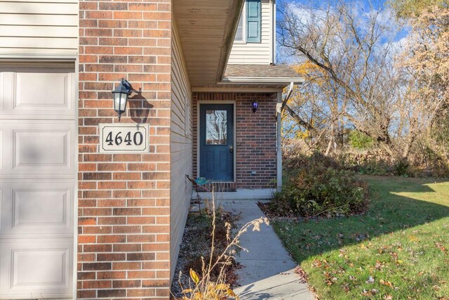 view of exterior entry with a garage and a yard