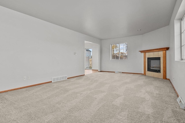 unfurnished living room featuring light carpet and a tile fireplace