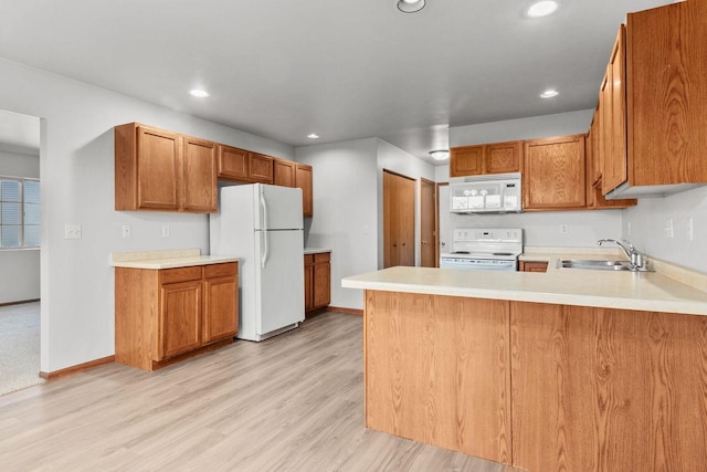 kitchen featuring kitchen peninsula, white appliances, sink, and light wood-type flooring