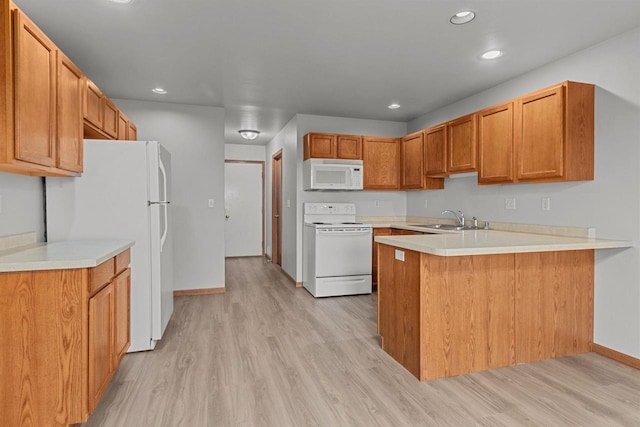 kitchen with kitchen peninsula, light hardwood / wood-style flooring, sink, and white appliances