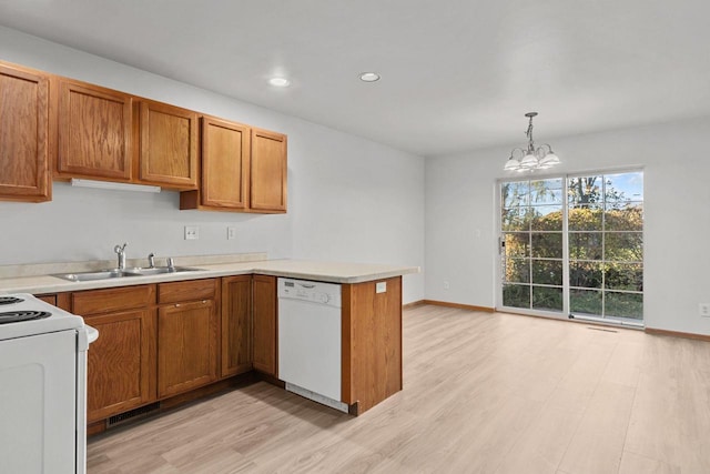 kitchen with white appliances, an inviting chandelier, sink, kitchen peninsula, and light hardwood / wood-style flooring