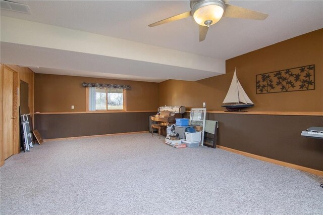 miscellaneous room featuring carpet, wood walls, and ceiling fan