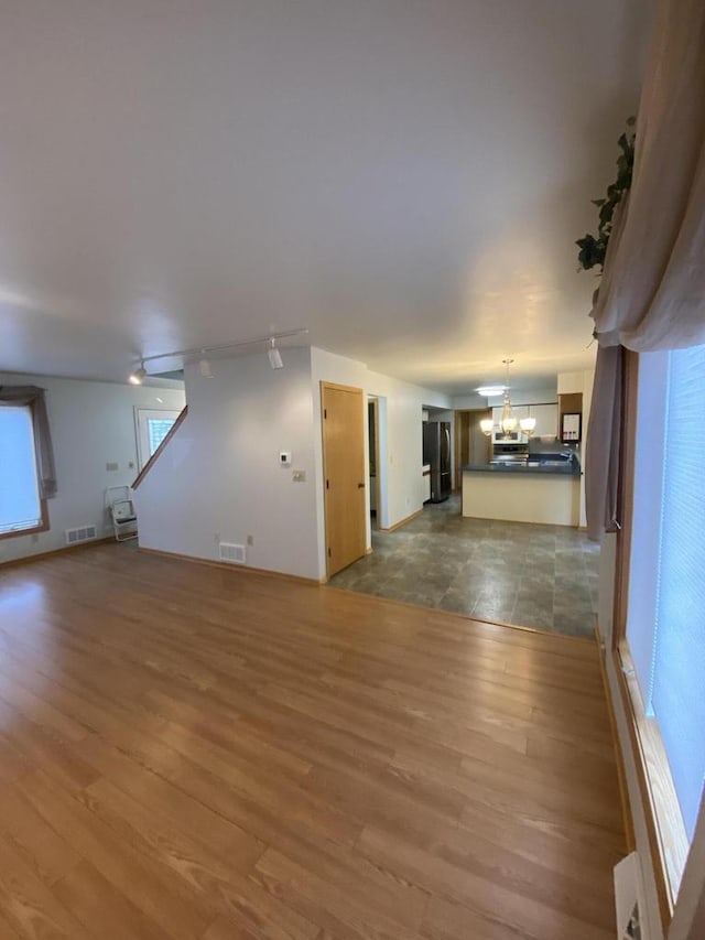 unfurnished living room featuring an inviting chandelier and dark hardwood / wood-style floors